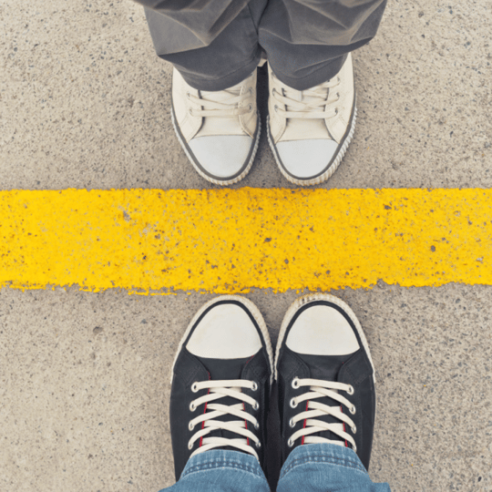 Sneakers from above. Two people standing toe to toe at dividing line